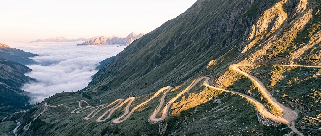 A mountain road climbing in switchbacks above the fog