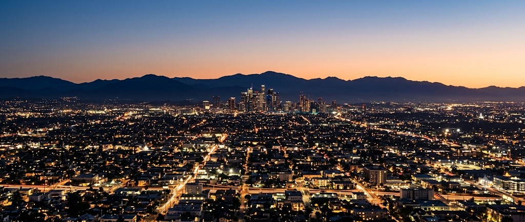 A city grid glowing at dusk beneath dark mountains