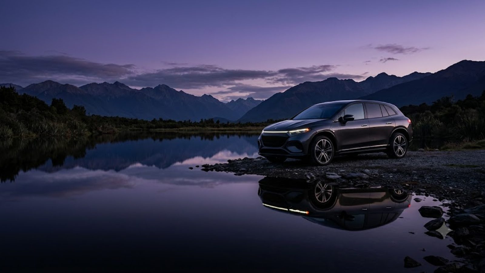 A luxury electric SUV parked at the edge of a still lake at dusk, its reflection perfect on the water
