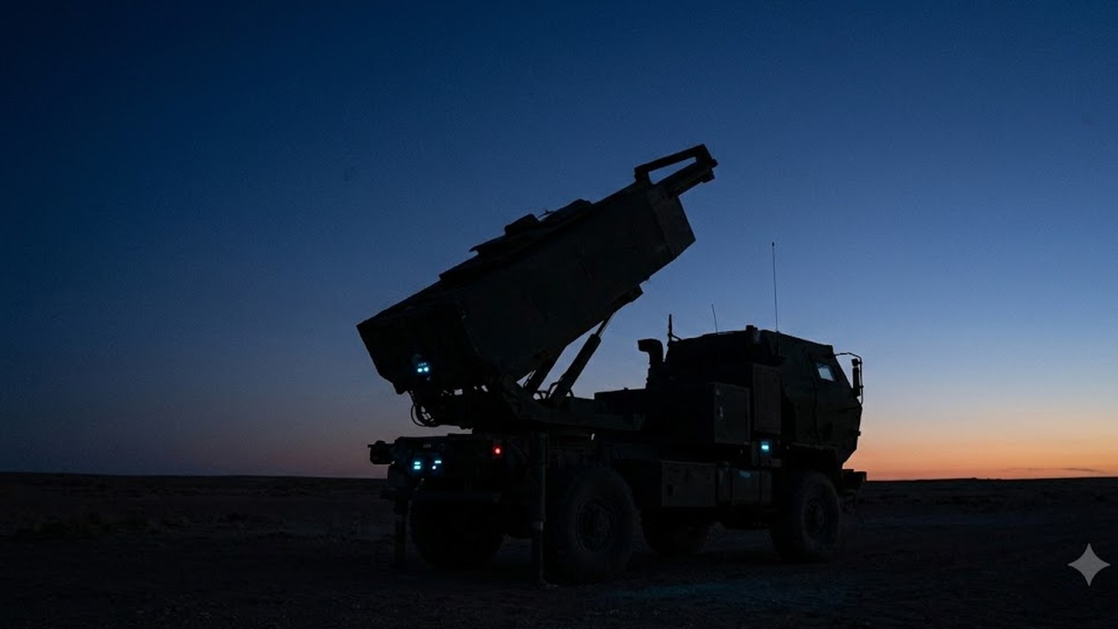 A truck-mounted missile launcher with its launch pod raised stands silhouetted on flat desert ground against a deep-blue dusk sky, a thin orange band on the horizon.