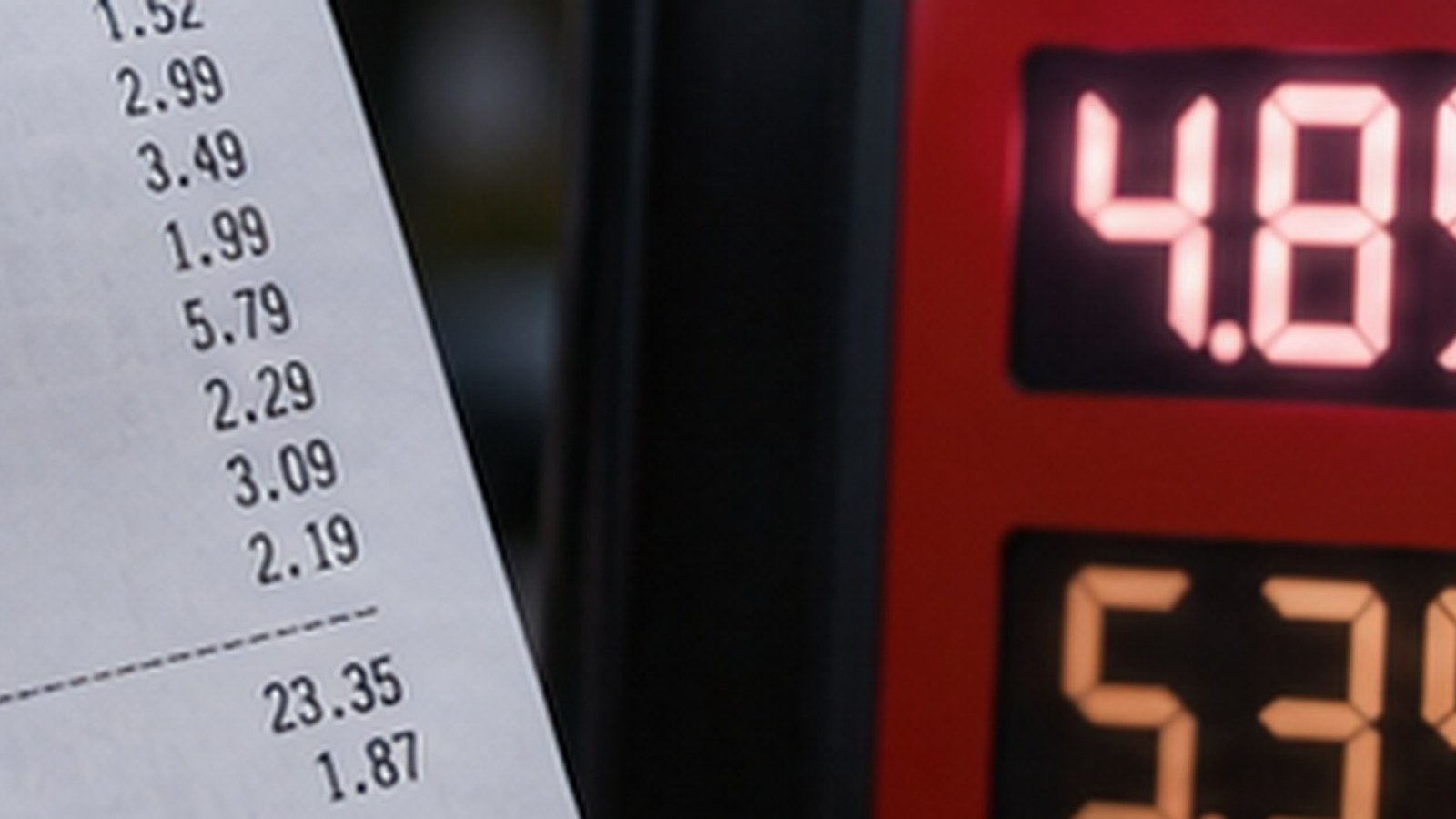 A close view of a long paper store receipt beside a gas pump's red price display glowing with numbers above five dollars, shot in soft focus.