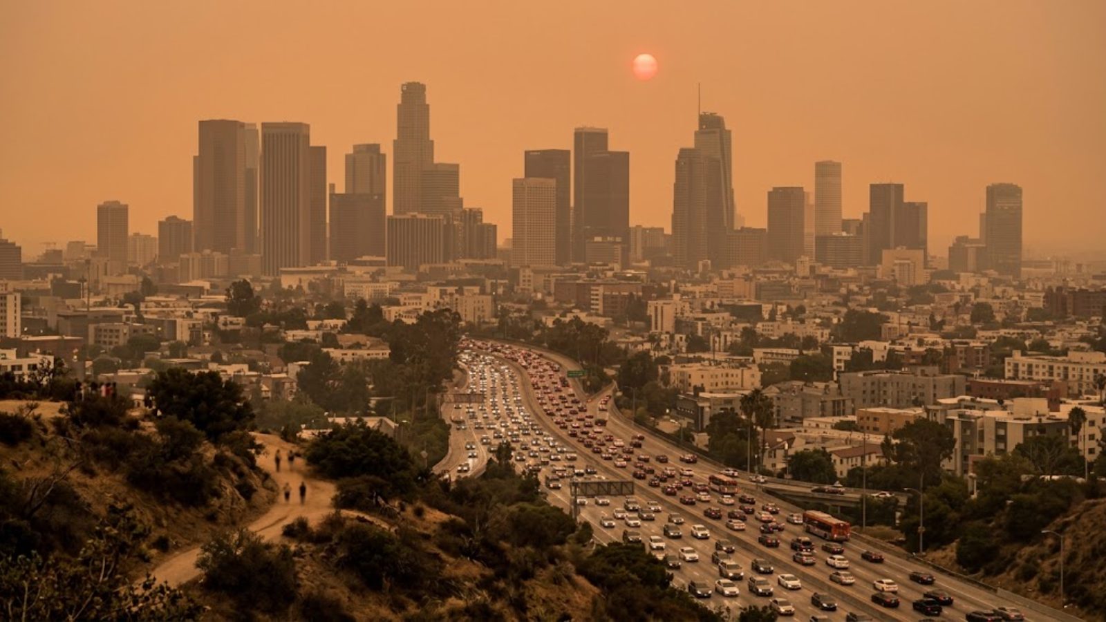 A hazy orange sun over a smoke-filled downtown Los Angeles skyline — the bill for the fire arrives long after the smoke clears.