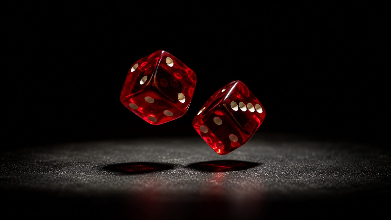 Two red translucent dice tumble through the air above a dark speckled surface, spotlit against a black background.