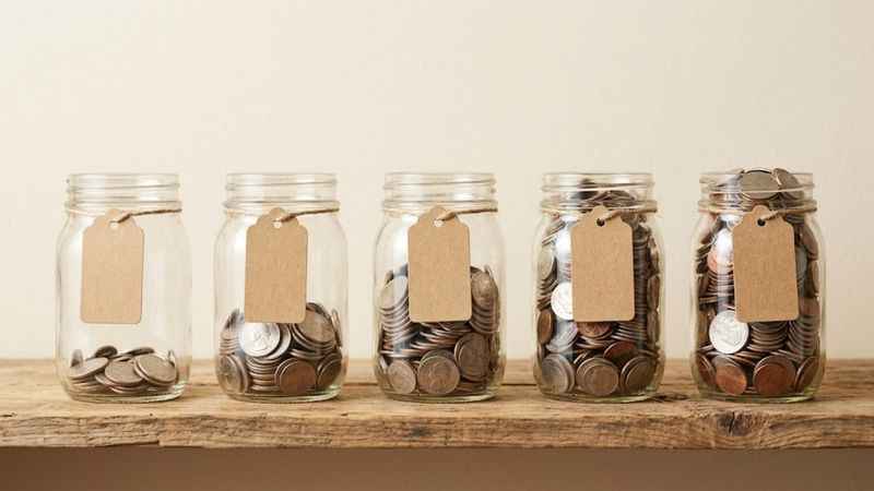 Glass jars of coins with blank tags, set aside in a row